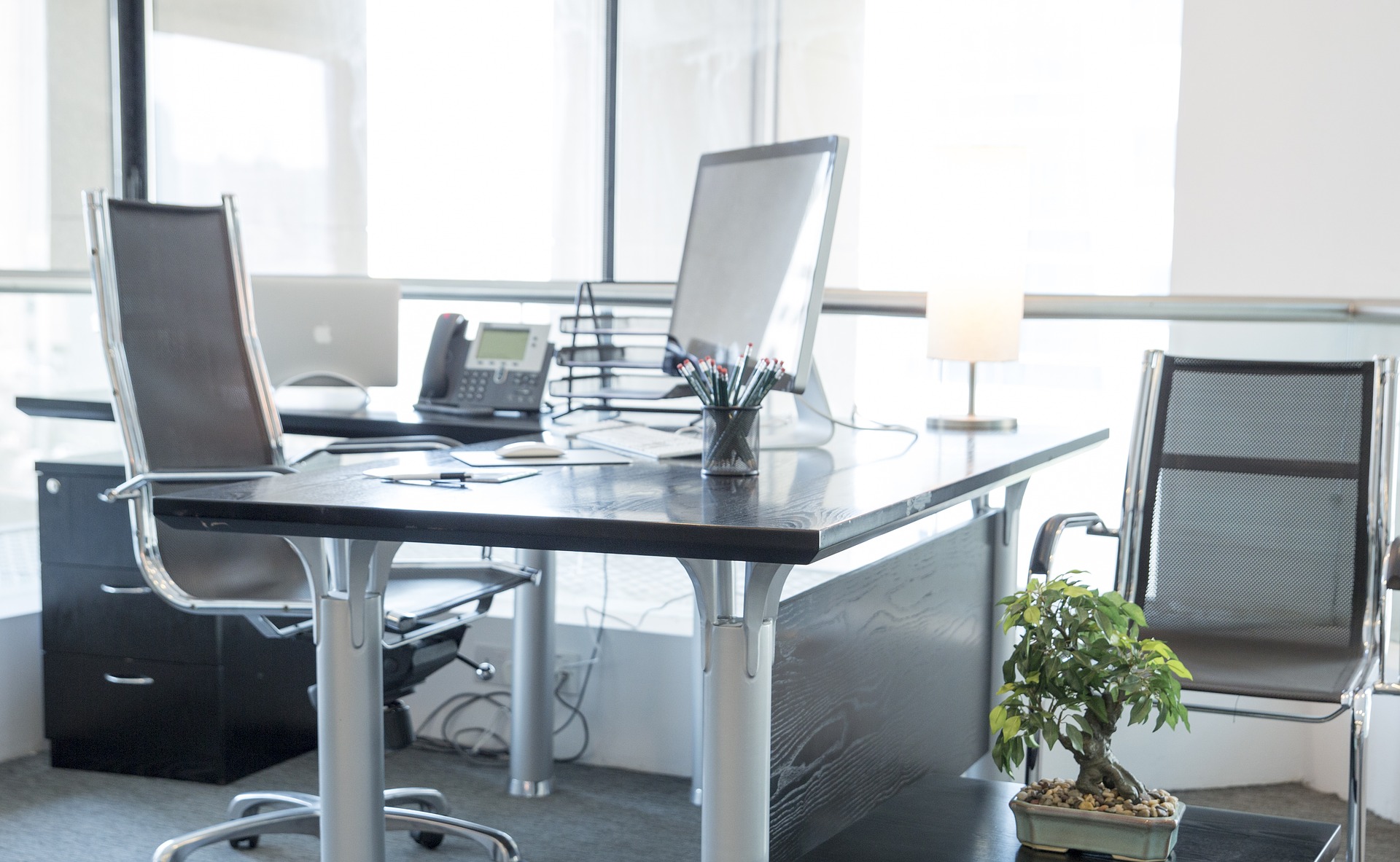 Office desk with computer, telephone and two chairs